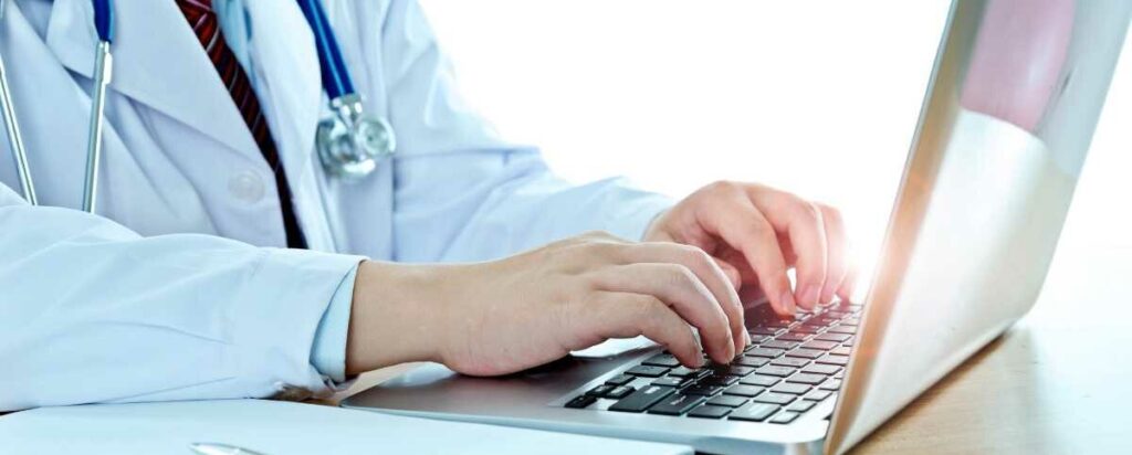 Physician typing on laptop